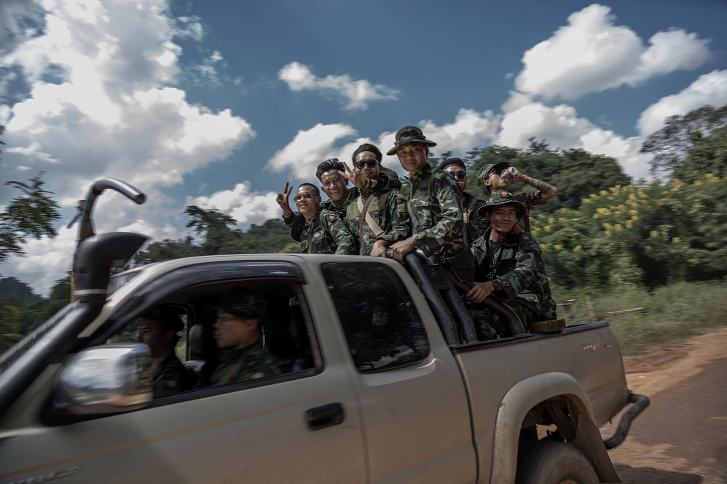 Troops smile and wave in the back of a truck