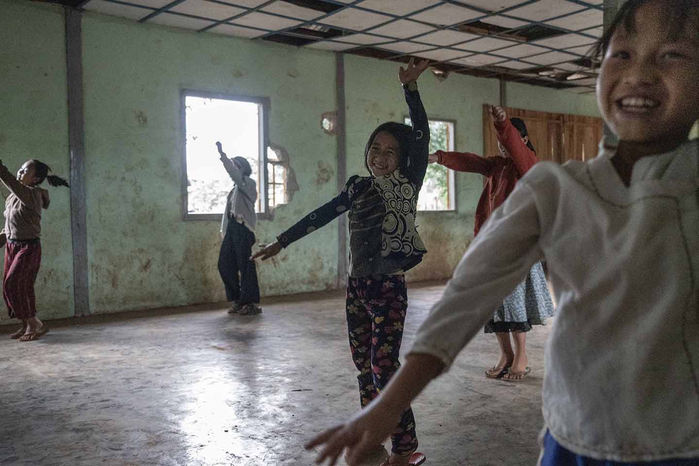 A group of children smile and raise their arms above their heads