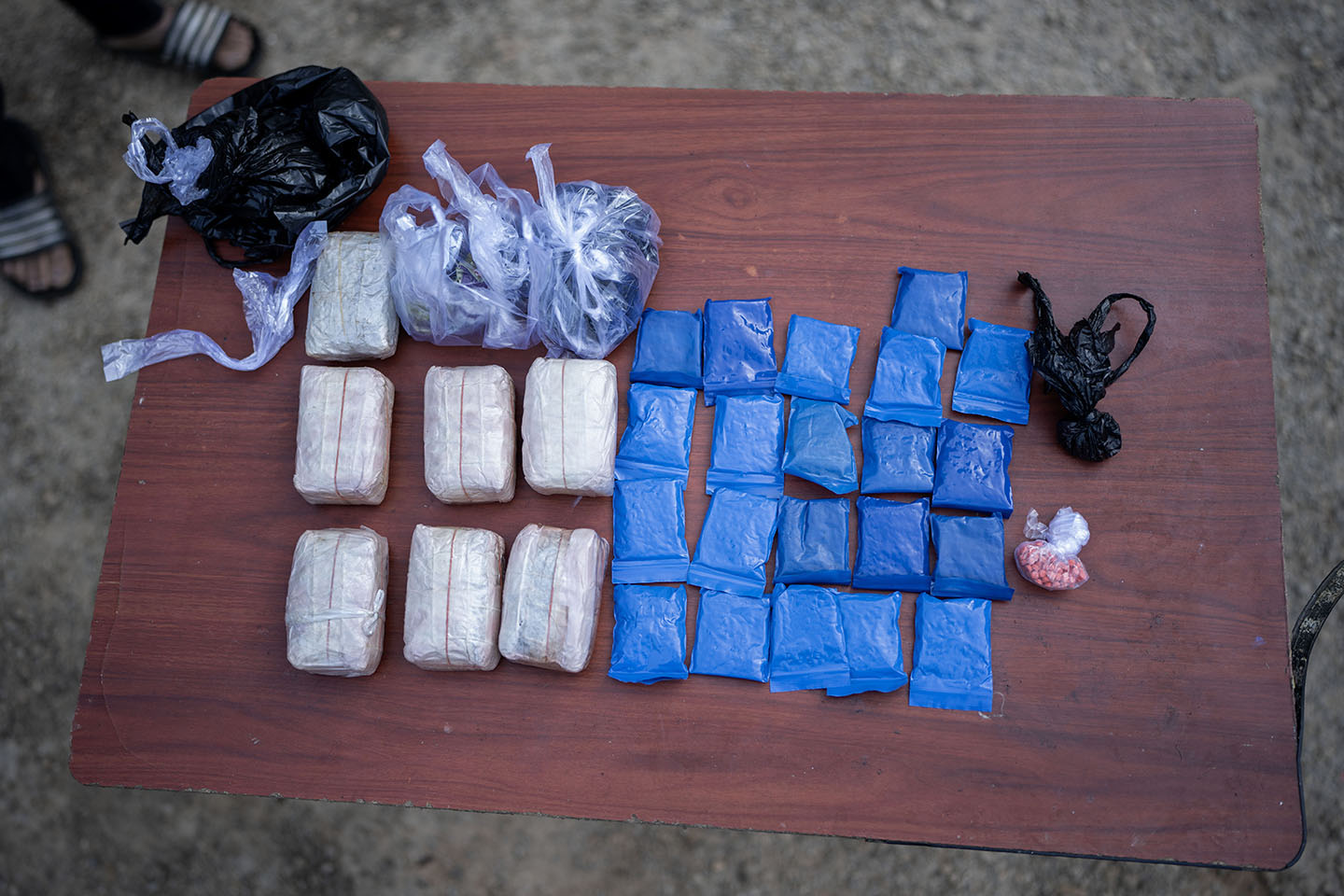 Clear and blue bags of drugs lay on a wooden table