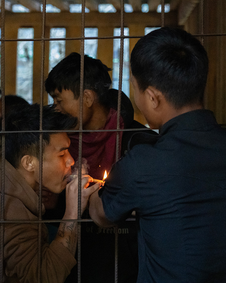 Officer lights a detainee's cigarette through bars