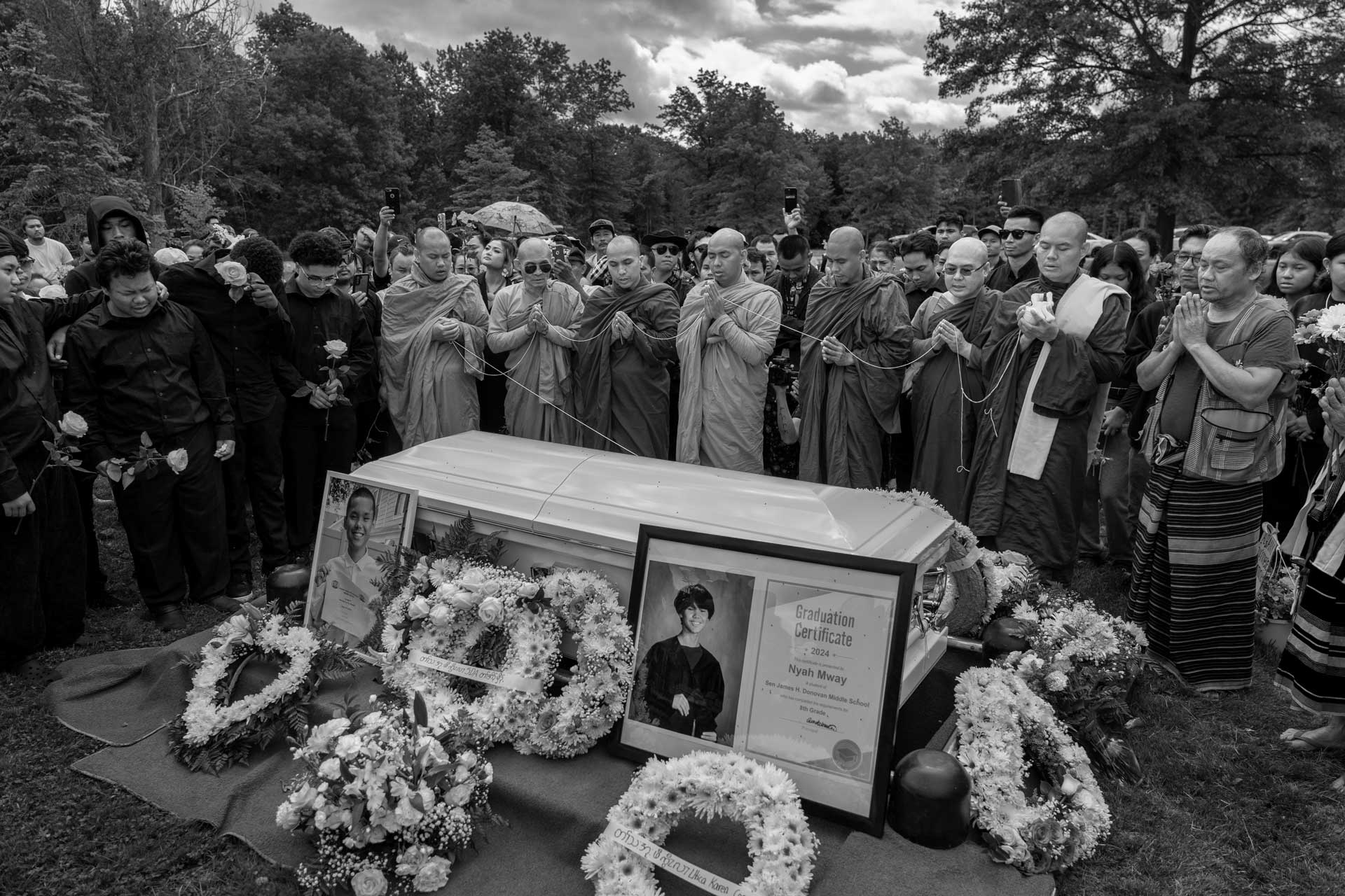 Buddhist monks chant as Thoung Oo, Nyah Mway’s eldest brother, and cousin Met Ka Pur Soe weep during the burial of Nyah Mway in Utica, New York, July 6, 2024.